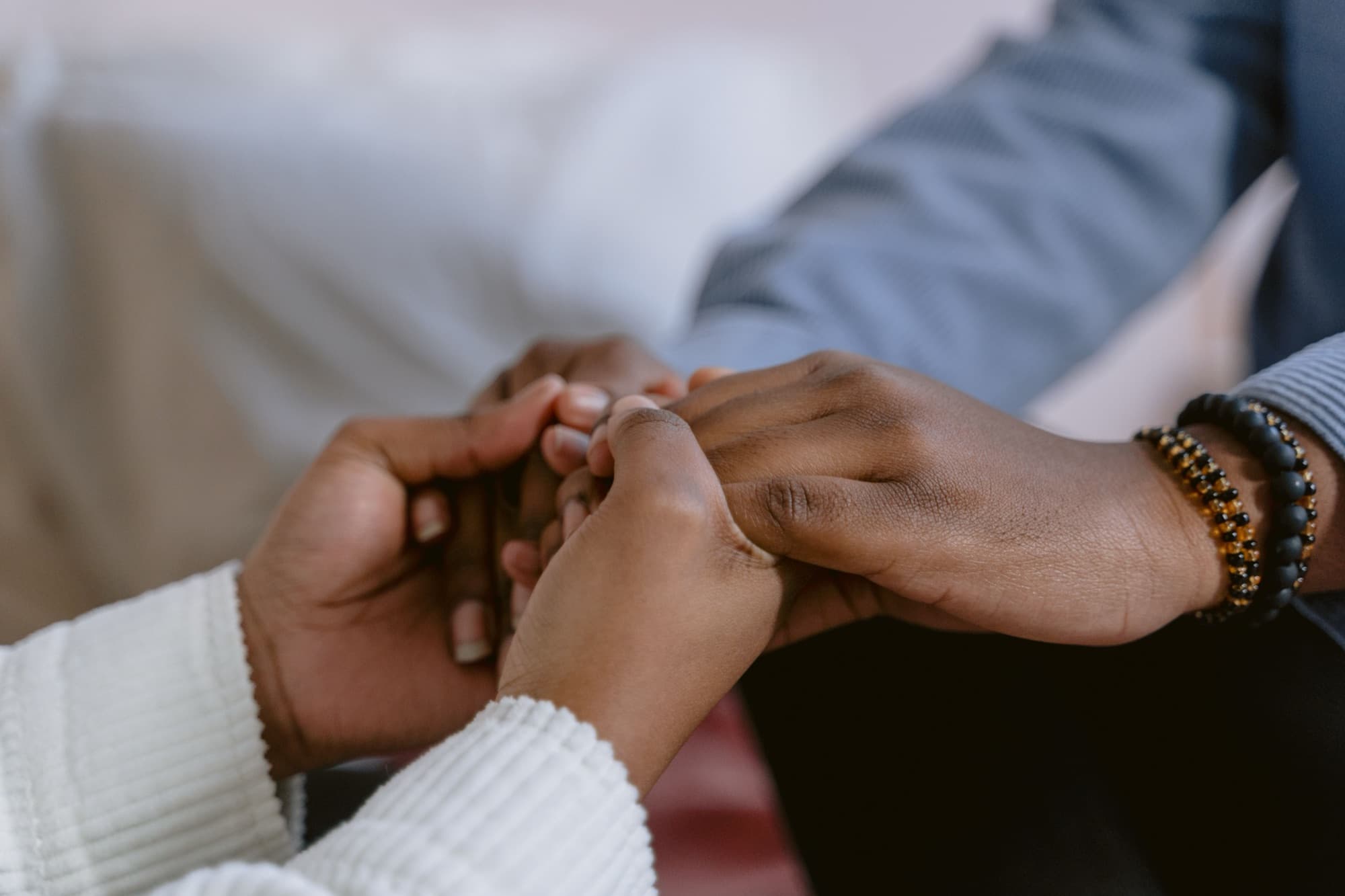 Two people clasping hands in a moment of comfort and support.