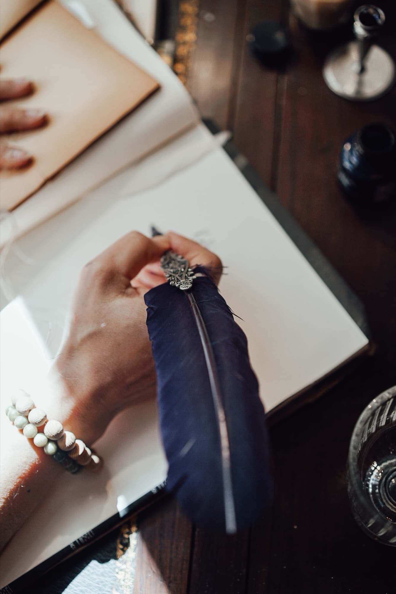 A hand writing in an open journal with a quill.